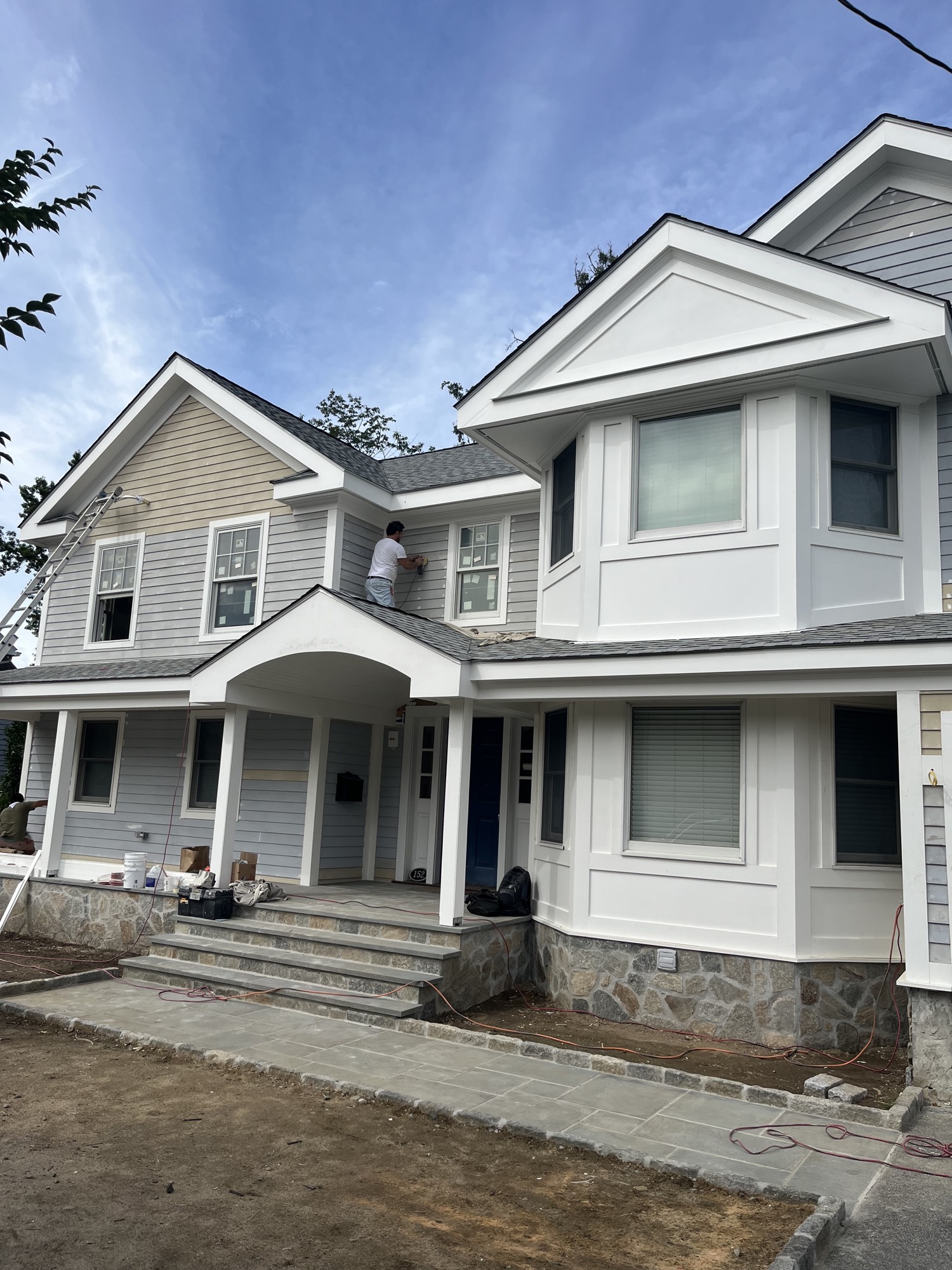 Same house with finished siding, white trim, portico and stone entry steps