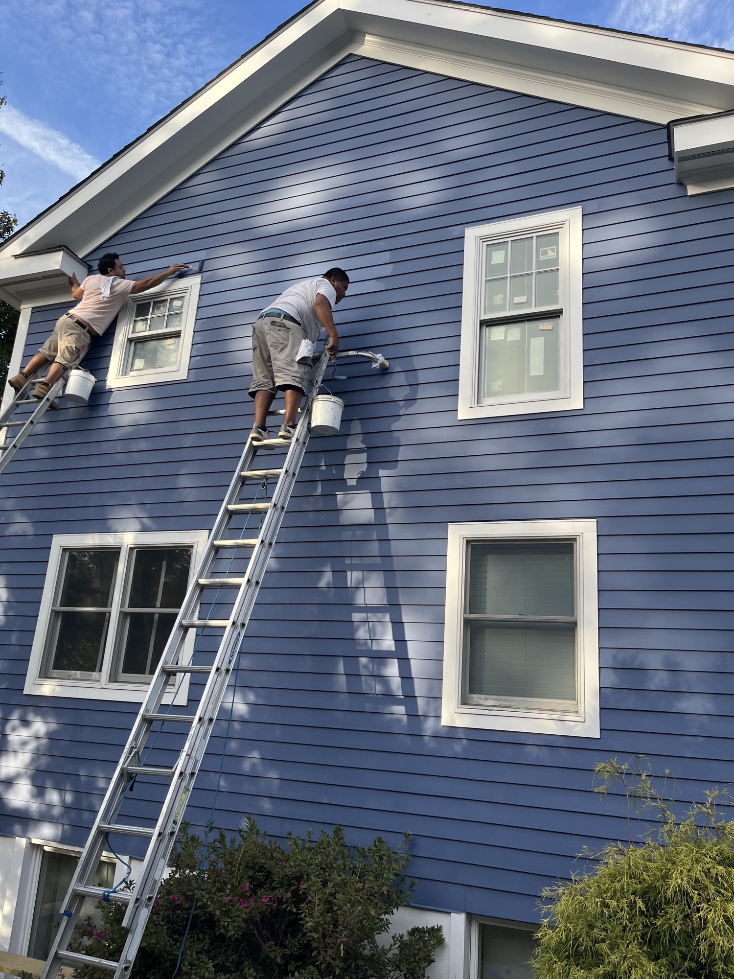 Painters finishing the blue siding and white trim